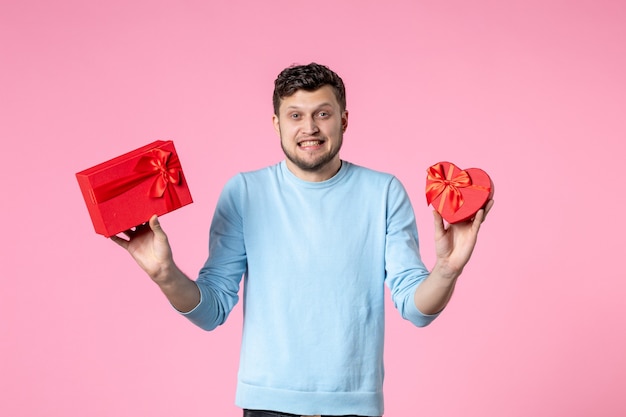 front view young male holding presents in red packages on pink background date marriage feminine sensual fun equality womens day march park