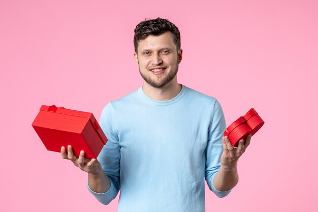 front view young male holding presents in red packages on pink background love date marriage feminine sensual fun womens day march equality