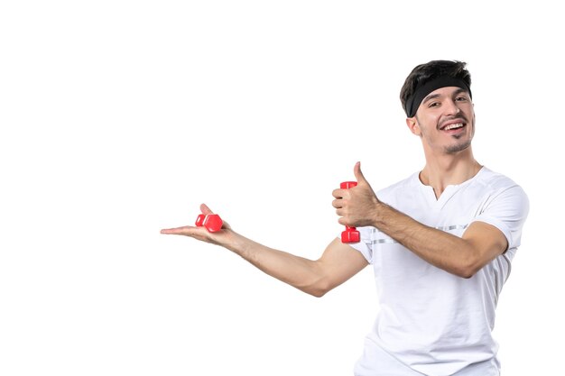 front view young male holding red dumbbells on white background diet health athlete yoga sport fit body color lifestyle