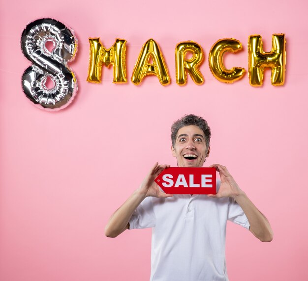 front view young male holding red sale nameplate with march decorated pink background glamour marriage love party sensual present money equality