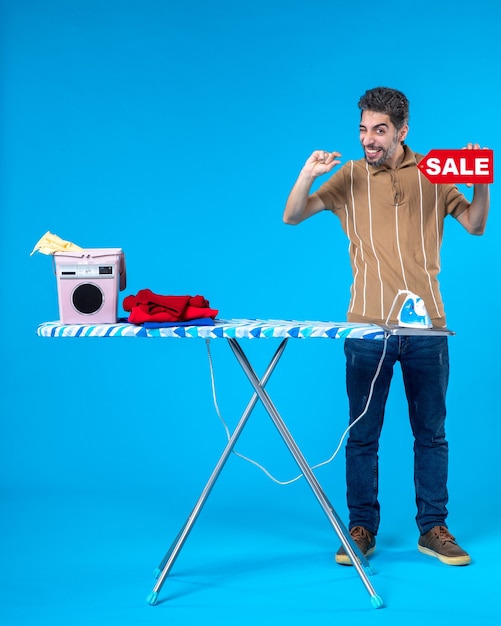 Photo front view young male holding red sale writing on blue background clean shopping housewife washing machine housework iron