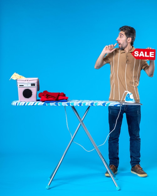 Front view young male holding red sale writing on blue background laundry clean shopping housewife washing machine housework iron