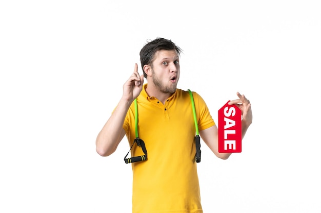 Foto vista frontale giovane maschio azienda vendita targhetta scritta su sfondo bianco lavoro sport umano shopping lavoratore uniforme gym
