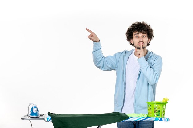 Front view young male behind ironing board on the white background housework ironing laundry cleaning emotion man color human