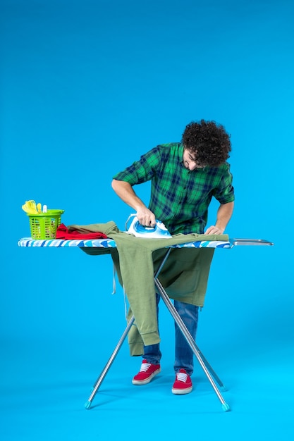 front view young male ironing green jersey on board on blue background human clean washing machine housework color house