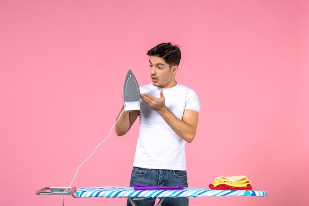 Front view young male ironing purple towel on a pink surface