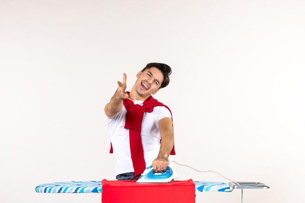 Front view young male ironing red towel on a white surface