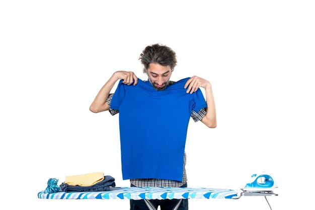 front view young male measuring blue shirt on himself on a white background housework work iron man home clothes clean machine laundry