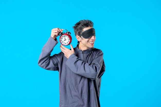 front view young male in pajamas holding red clocks on blue background dark nightmare insomnia night color sleep late dream