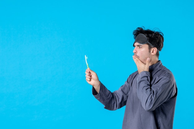 front view young male in pajamas holding toothbrush on blue background dream nightmare night color wake clean human bed pain