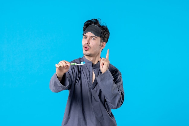 front view young male in pajamas holding toothbrush on blue background nightmare bed night color rest wake clean dream