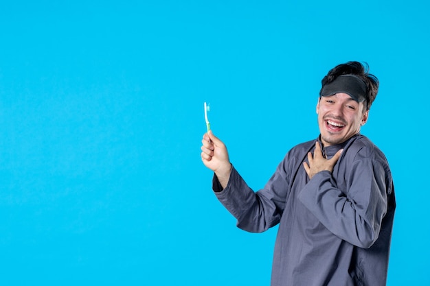 front view young male in pajamas holding toothbrush and laughing on blue background color dream nightmare night wake clean human bed