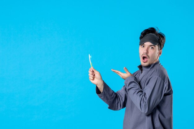 front view young male in pajamas holding toothbrush with surprised expression on blue background dream nightmare night color wake human bed