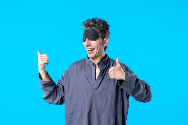 front view young male in pajamas and sleeping bandage on blue background color rest night nightmare sleep dark bedroom dream