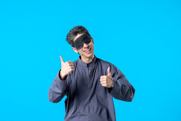 front view young male in pajamas with bandage for sleep smiling and showing alright sign on blue background color sleep dream night bed nightmare bedroom dark