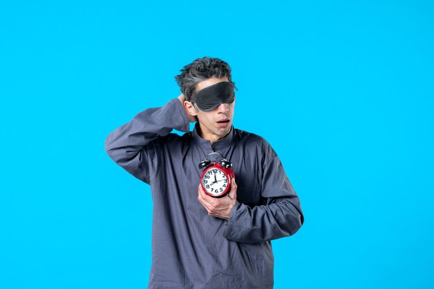 front view young male in pajamas with red clocks on blue background dark nightmare insomnia late sleep dream bed night color