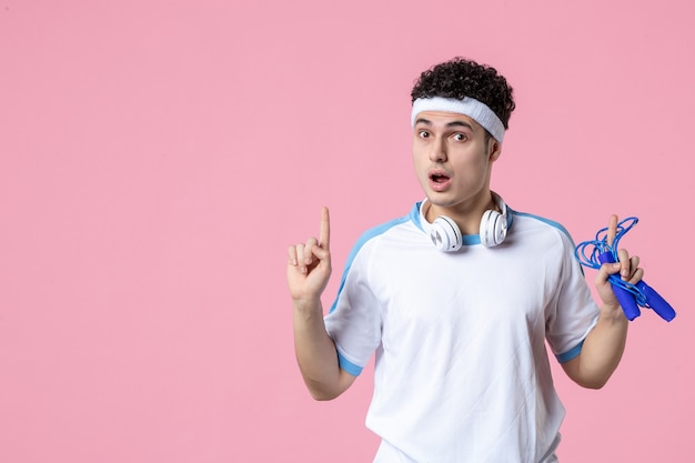 Front view young male in sport clothes with skipping rope on pink wall