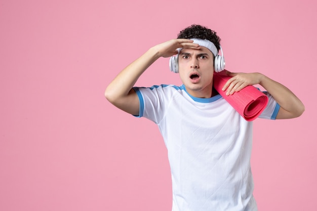 Front view young male in sport clothes with yoga mat on pink wall