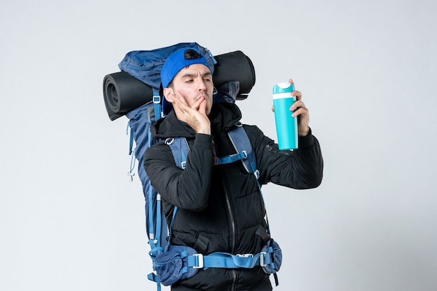 front view young male with backpack holding empty thermos on white background mountain camp nature cold campaign air tent snow