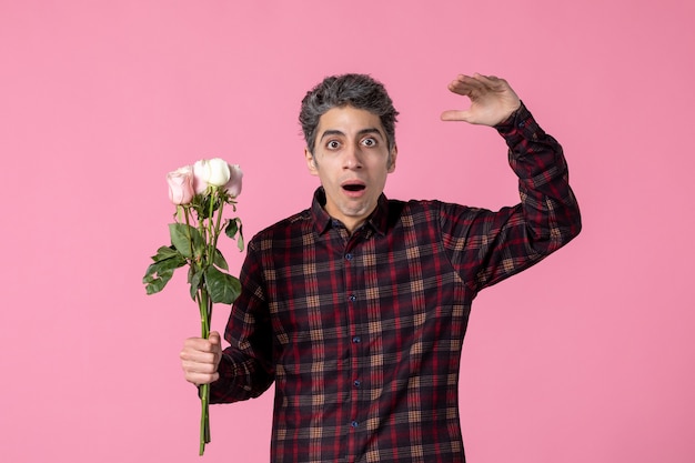 Front view young male with beautiful pink roses on pink wall