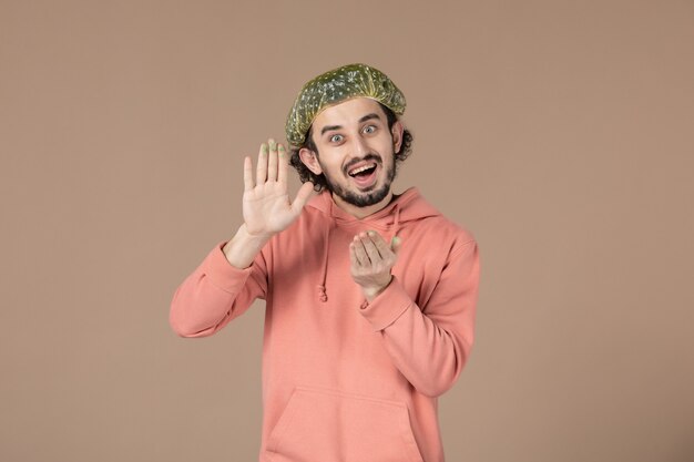 front view young male with bouffant cap on brown background salon skincare massaging therapy hair facial spa