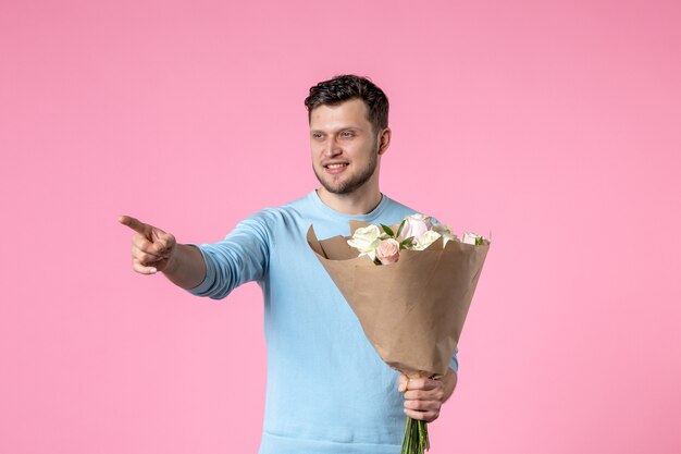 Front view young male with bouquet of beautiful flowers on pink\
background marriage date park sensual womens day march equality\
love feminine fun