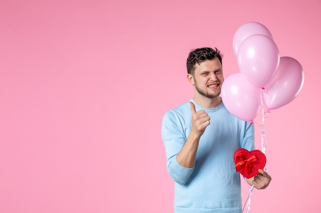 front view young male with cute pink balloons and heart shaped present on pink background park sensual womens day march feminine fun love marriage equality