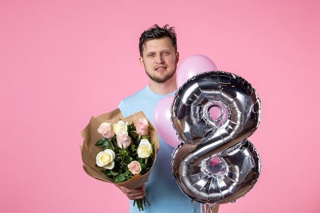 ピンクの背景に3月のように花と風船を持つ若い男性の正面図平等結婚愛女性の日女性の日付水平