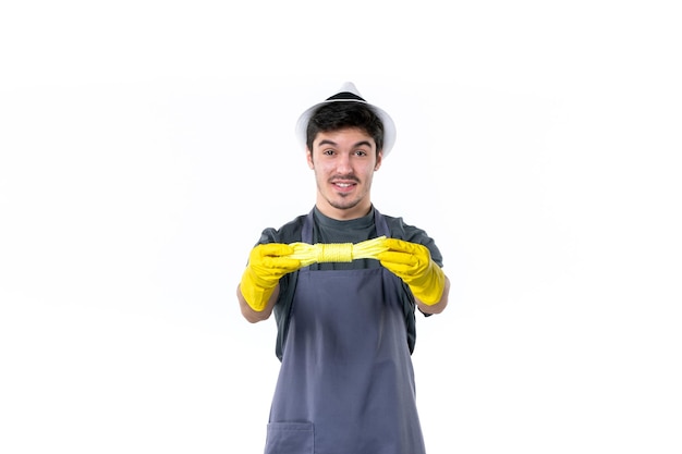 Front view young male in yellow gloves holding ropes on a white background flower plant garden grass tree gardener green job bush