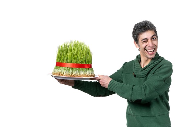 front view of young man holding big traditional novruz semeni on white wall