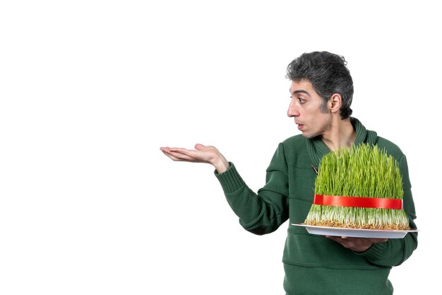 front view of young man holding big traditional novruz semeni on white wall