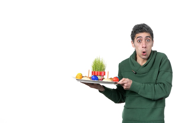 front view of young man holding traditional novruz xoncha on white wall