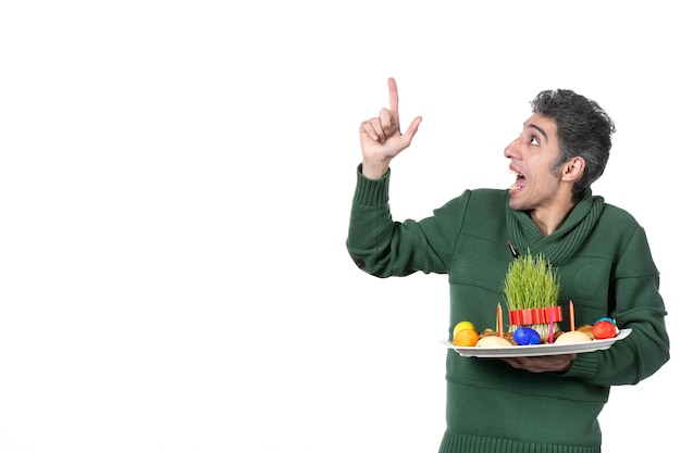 front view of young man holding traditional novruz xoncha on white wall