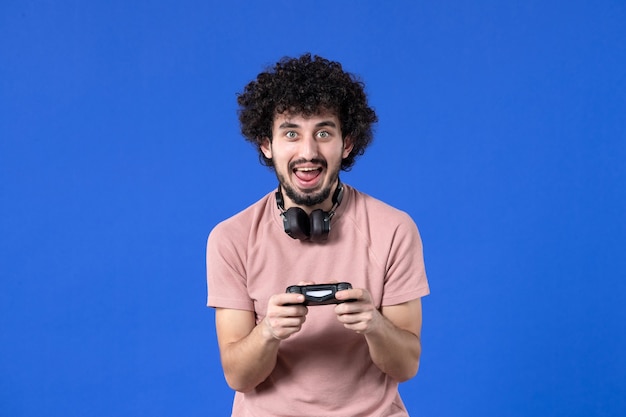 front view young man playing video game with black gamepad on blue background teen youth winning player sofa adult virtual soccer