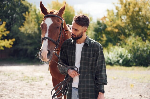 Photo front view young man with a horse is outdoors