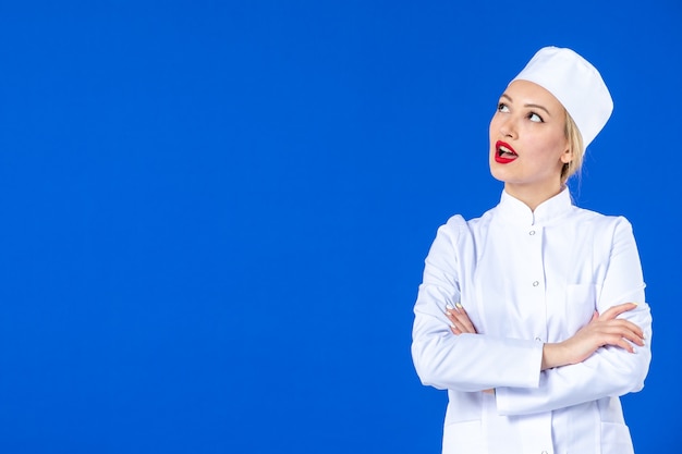 front view of young nurse in medical suit on blue wall