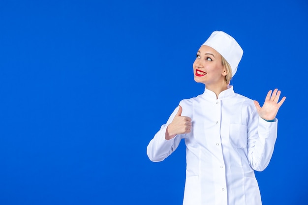 front view of young nurse in medical suit on blue wall