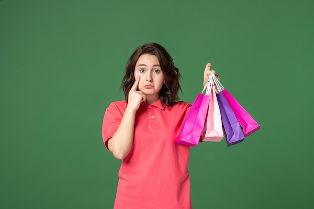 Front view young saleswoman holding gift packages on green surface