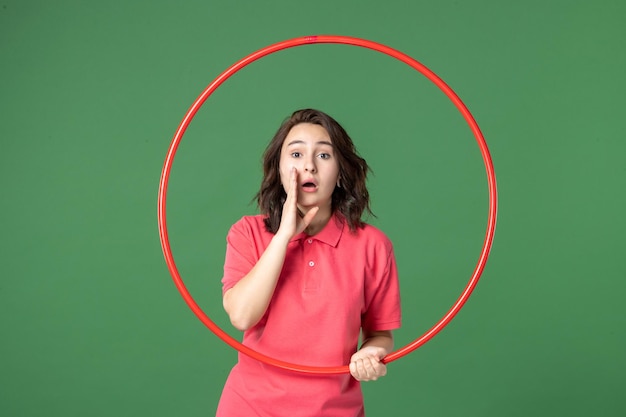 Front view young saleswoman holding red hula hoop on green surface