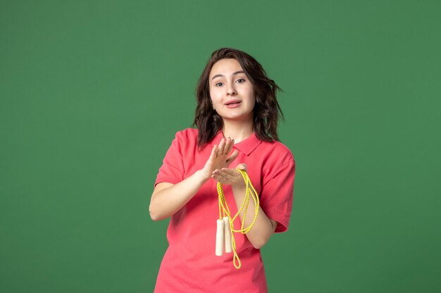 Front view young saleswoman holding skipping rope and clapping on green surface