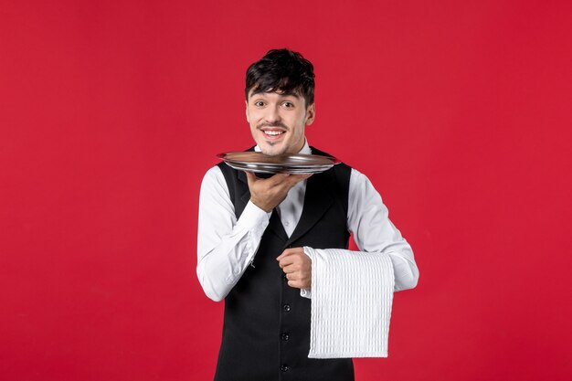 Front view of young smiling male waiter in a uniform with tie bow