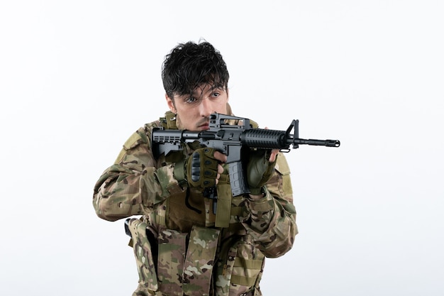 Front view young soldier fighting in camouflage with machine gun white wall