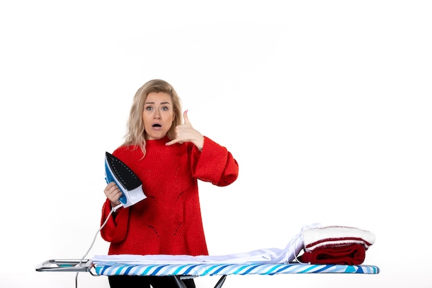 Photo front view of young surprised beautiful woman holding iron making call me gesture on white background