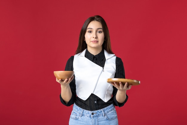 Foto vista frontale giovane cameriera in possesso di ordini di cibo su sfondo rosso lavoro cibo lavoro pasto bellezza lavoratore sera donna colore cena uniform