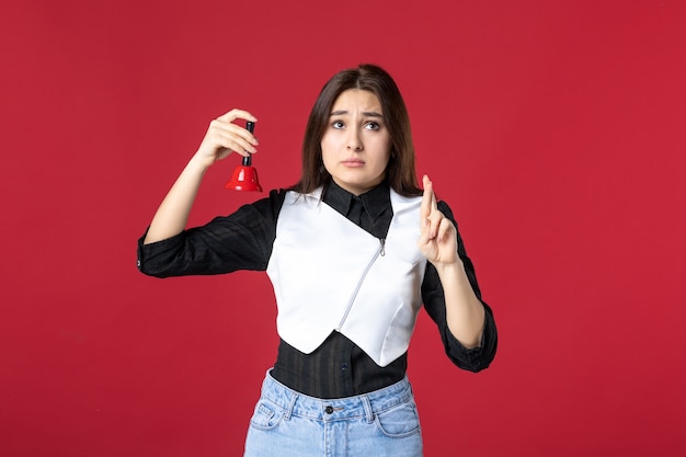 front view young waitress in uniform holding little bell on red background dinner evening work job cafe restaurant woman beauty color