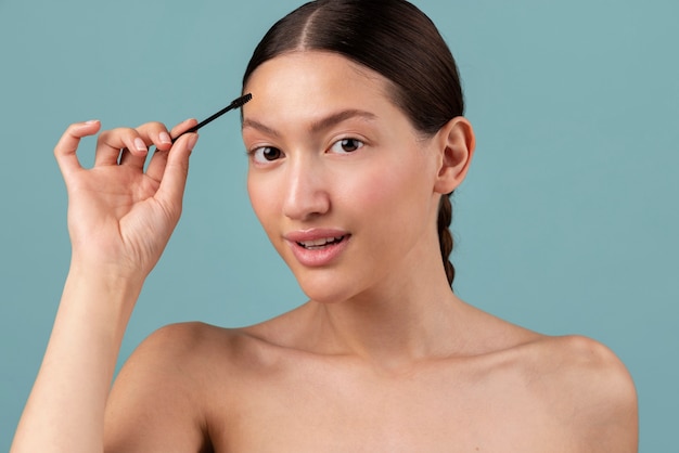 Photo front view young woman using  brow brush