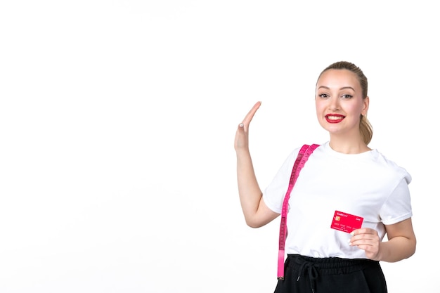 Вид спереди молодая женщина с рулеткой и кредитной картой на белом фоне.
