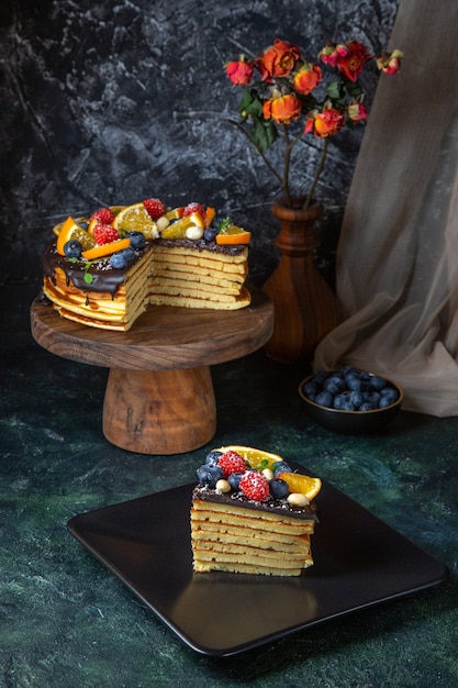 Torta al cioccolato gustosa vista frontale con frutta sulla parete scura