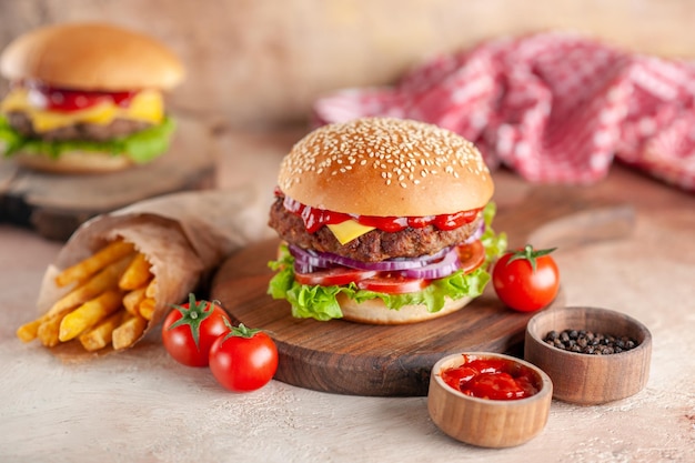 Вид спереди вкусный мясной чизбургер с картофелем фри на разделочной доске светлый фон салат ужин закуска фаст-фуд бургер