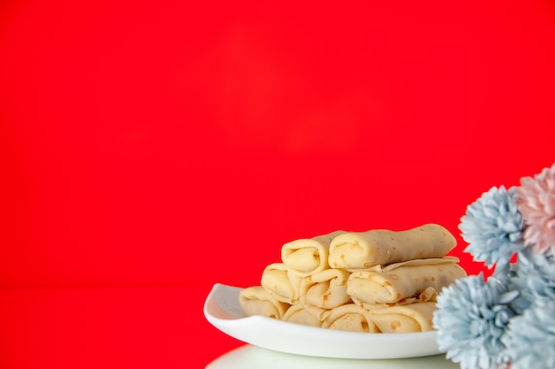 Front view yummy rolled pancakes on red background breakfast cake sugar dessert color milk flower sweet morning